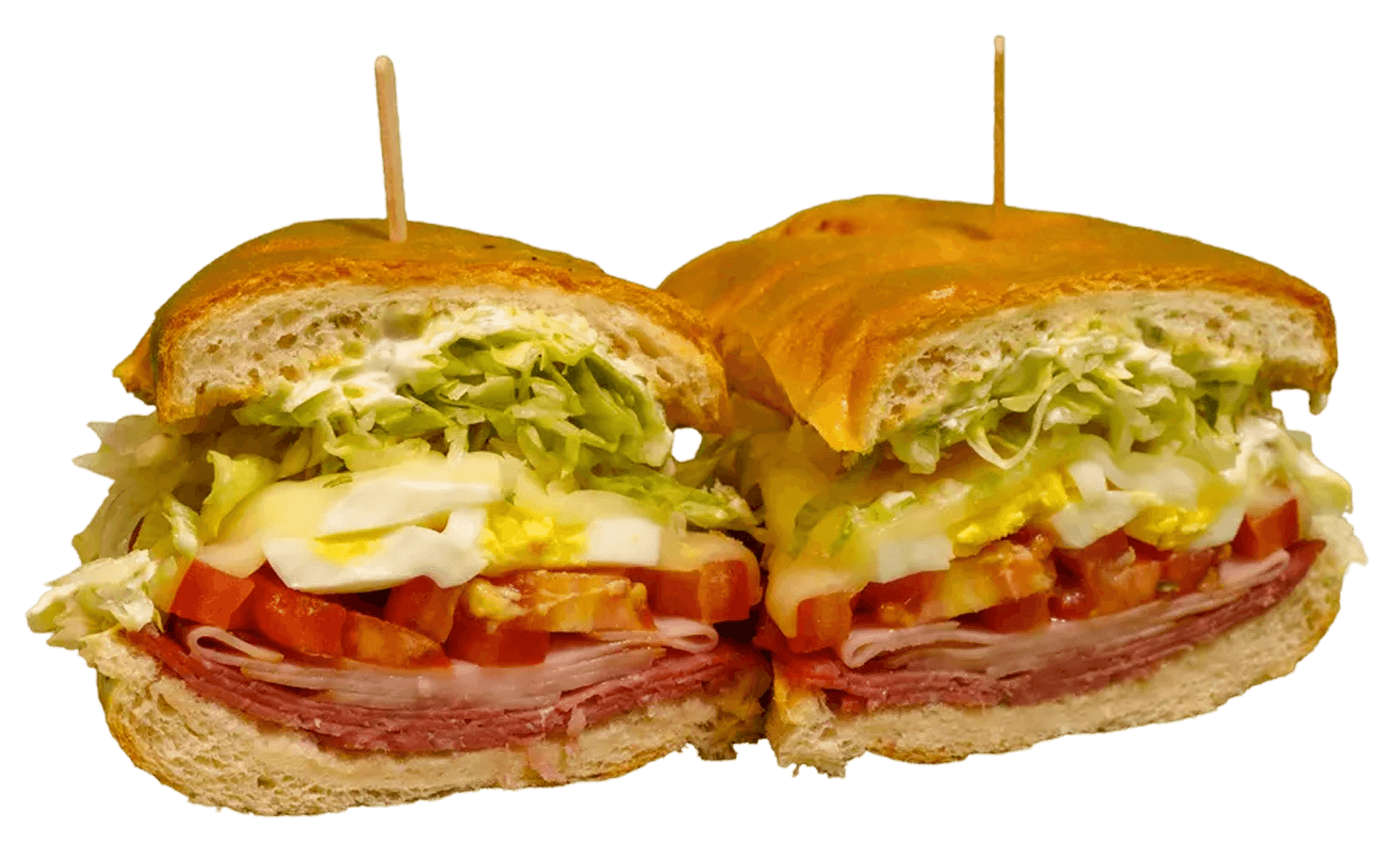 Multi-grain baguette sandwich filled with sliced chicken, yellow cheese, lettuce, pesto, and sun-dried tomatoes, served on a white plate.