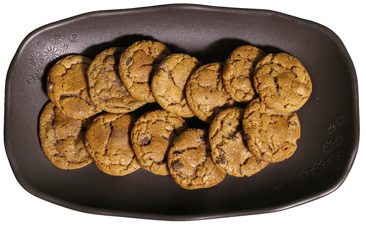 Golden brown chocolate chip cookies with visible chips and crinkled tops, arranged on a dark brown serving platter with embossed floral designs.