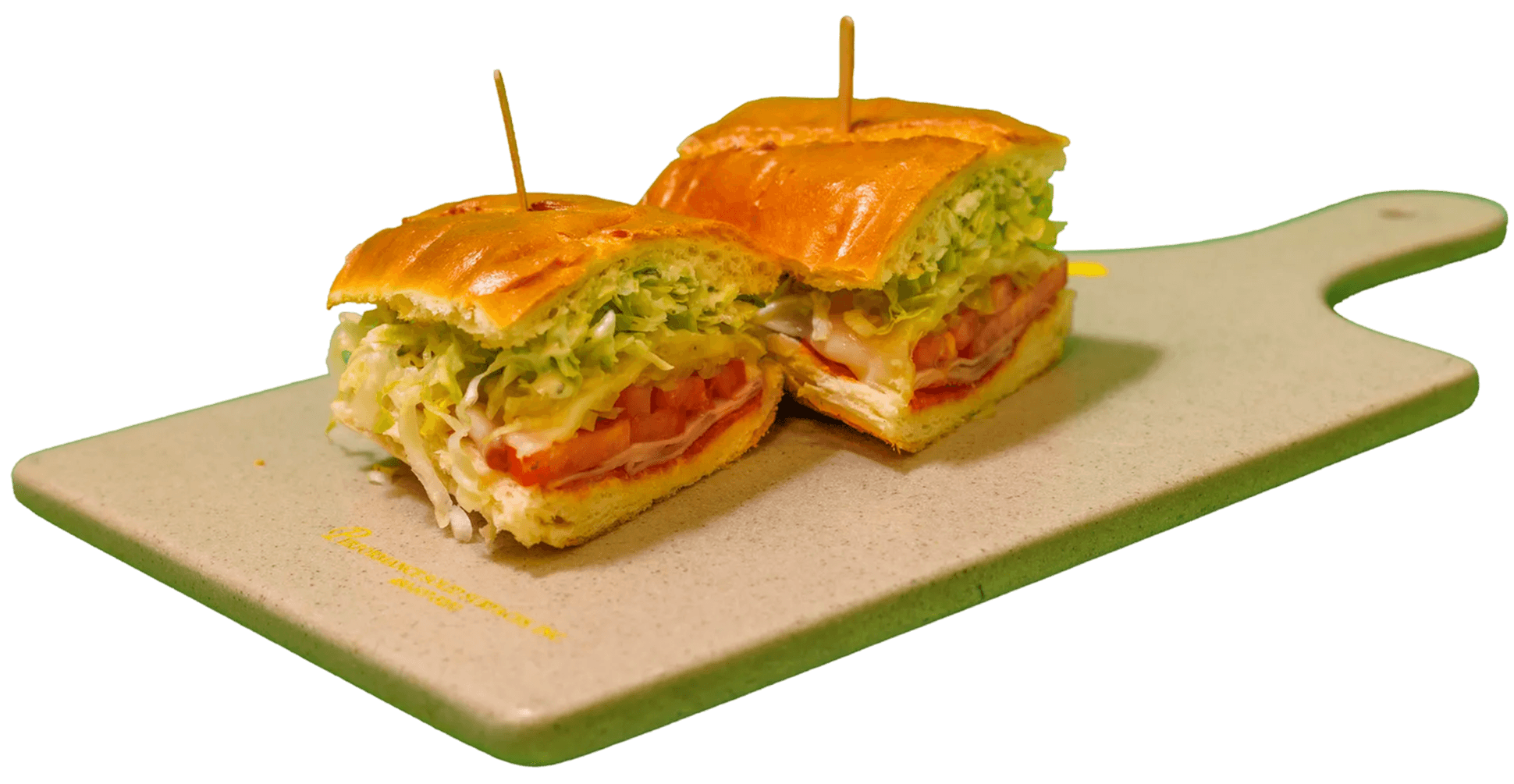 A submarine sandwich, cut in half and held by toothpicks, displays its fillings of shredded lettuce, sliced tomatoes, deli meat, and sauce on a beige cutting board.