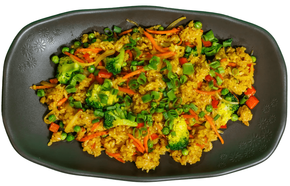 Curry fried rice with broccoli, carrots, peas, and red bell peppers, garnished with green onions, served on a dark oblong plate with a floral pattern.